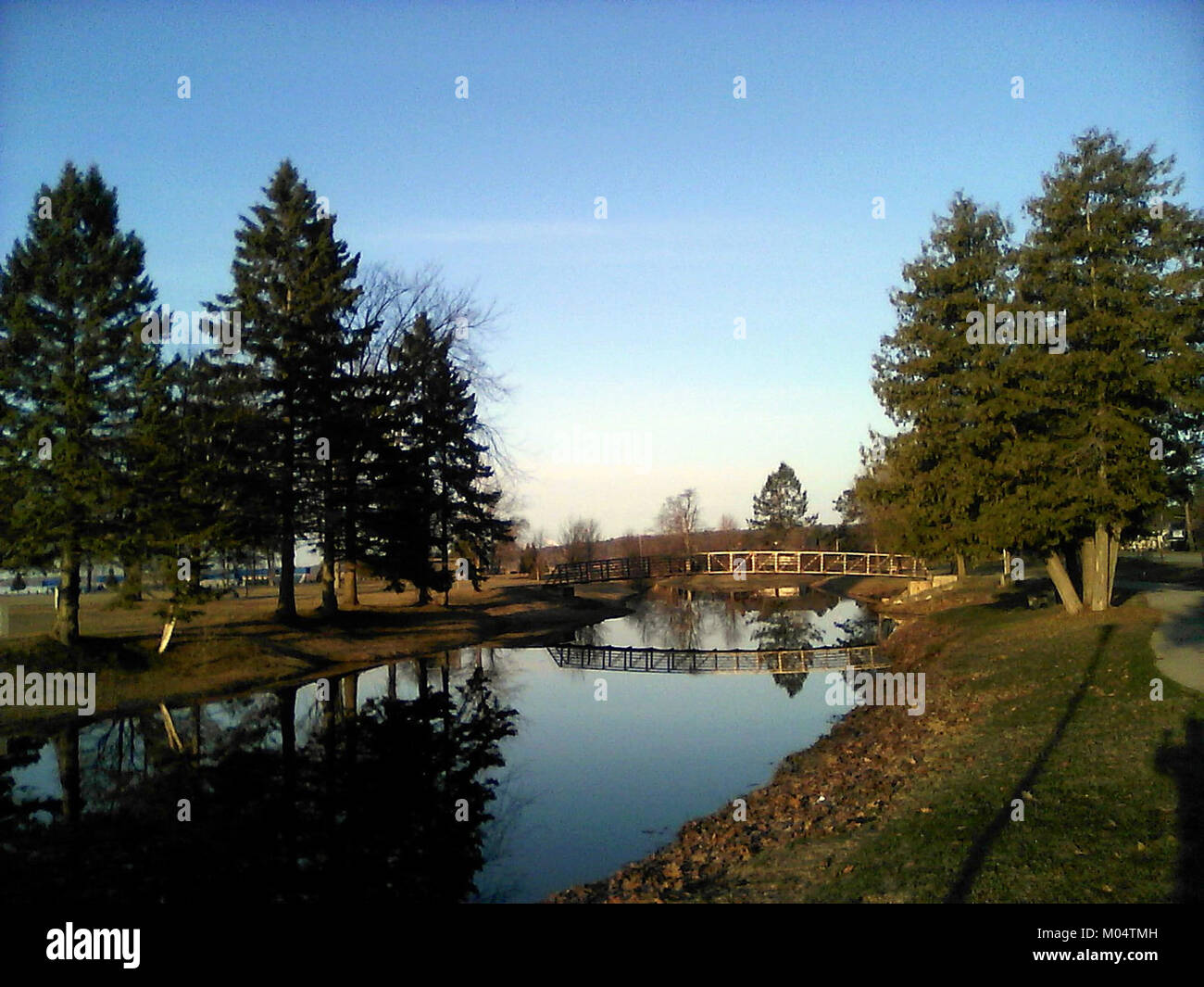 L'immagine cattura il riflesso di un ponte in acqua, sottolineando la simmetria e il design architettonico del ponte. La riflessione aggiunge una dimensione artistica alla struttura, esaltandone l'attrattiva visiva. Questo concetto viene spesso utilizzato nella fotografia per evidenziare il legame tra architettura e natura. Foto Stock