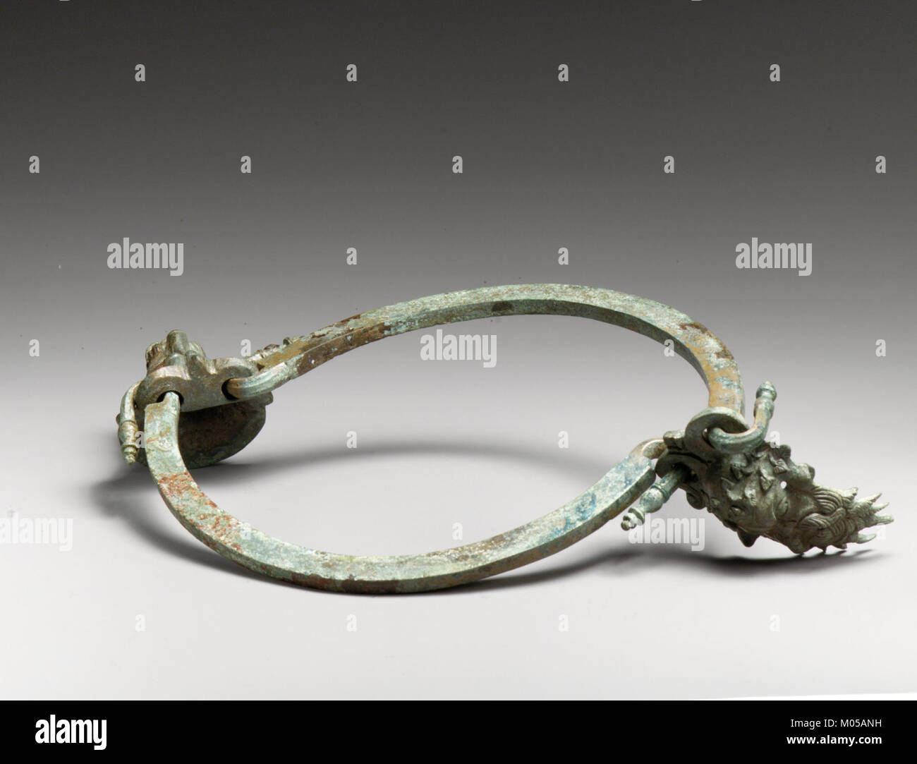 L'impugnatura in bronzo di una situla, o secchiello, presenta dettagli intricati come un attacco per la testa Silenos e un boccaglio per la testa di leone. Questi elementi riflettono l'antica maestria artistica nella lavorazione dei metalli. Foto Stock