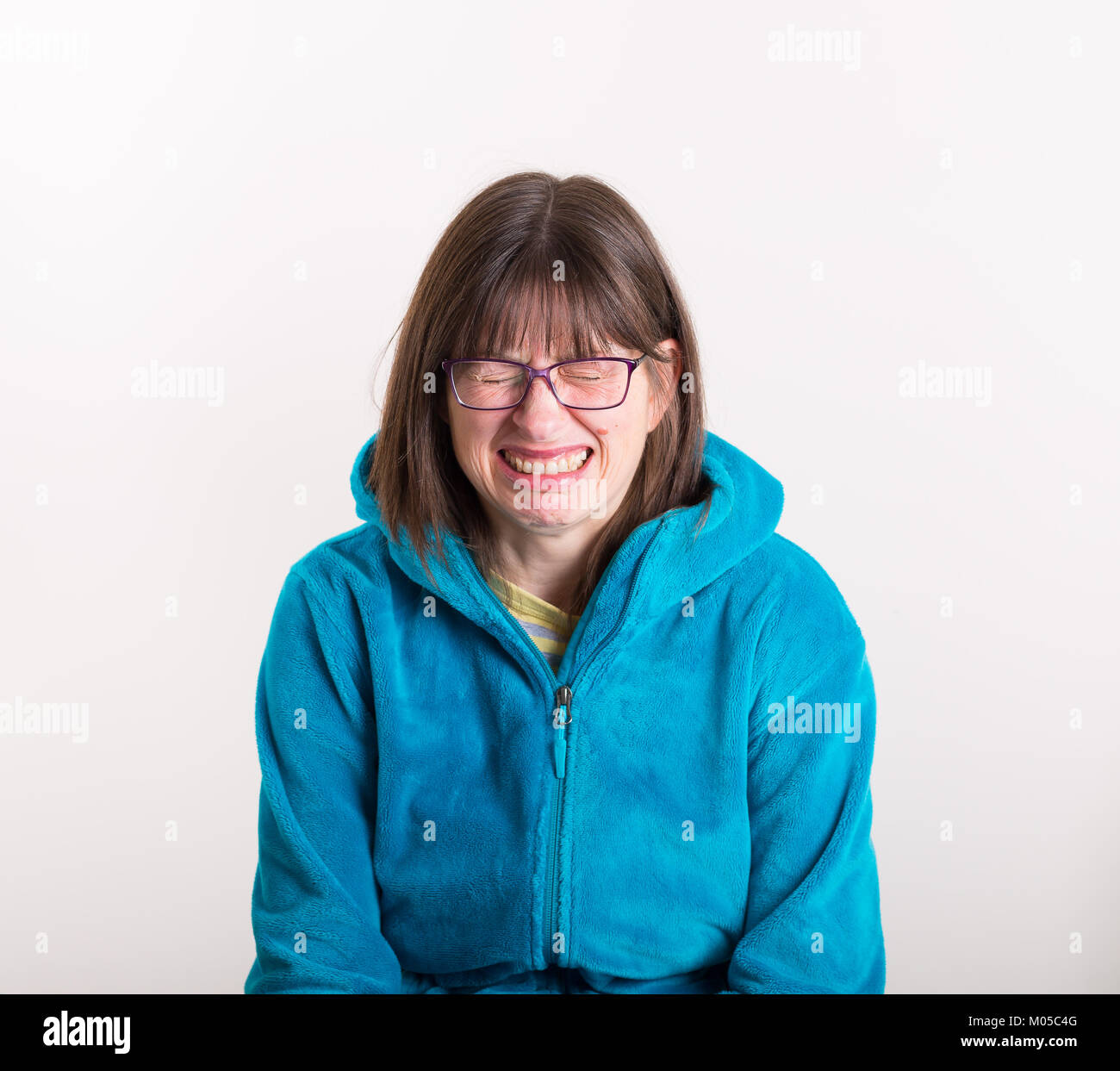 Foto in studio d'interni di una giovane donna isolata che indossa gli occhiali, che crea un volto e dà un'espressione di totale disgusto! Foto Stock