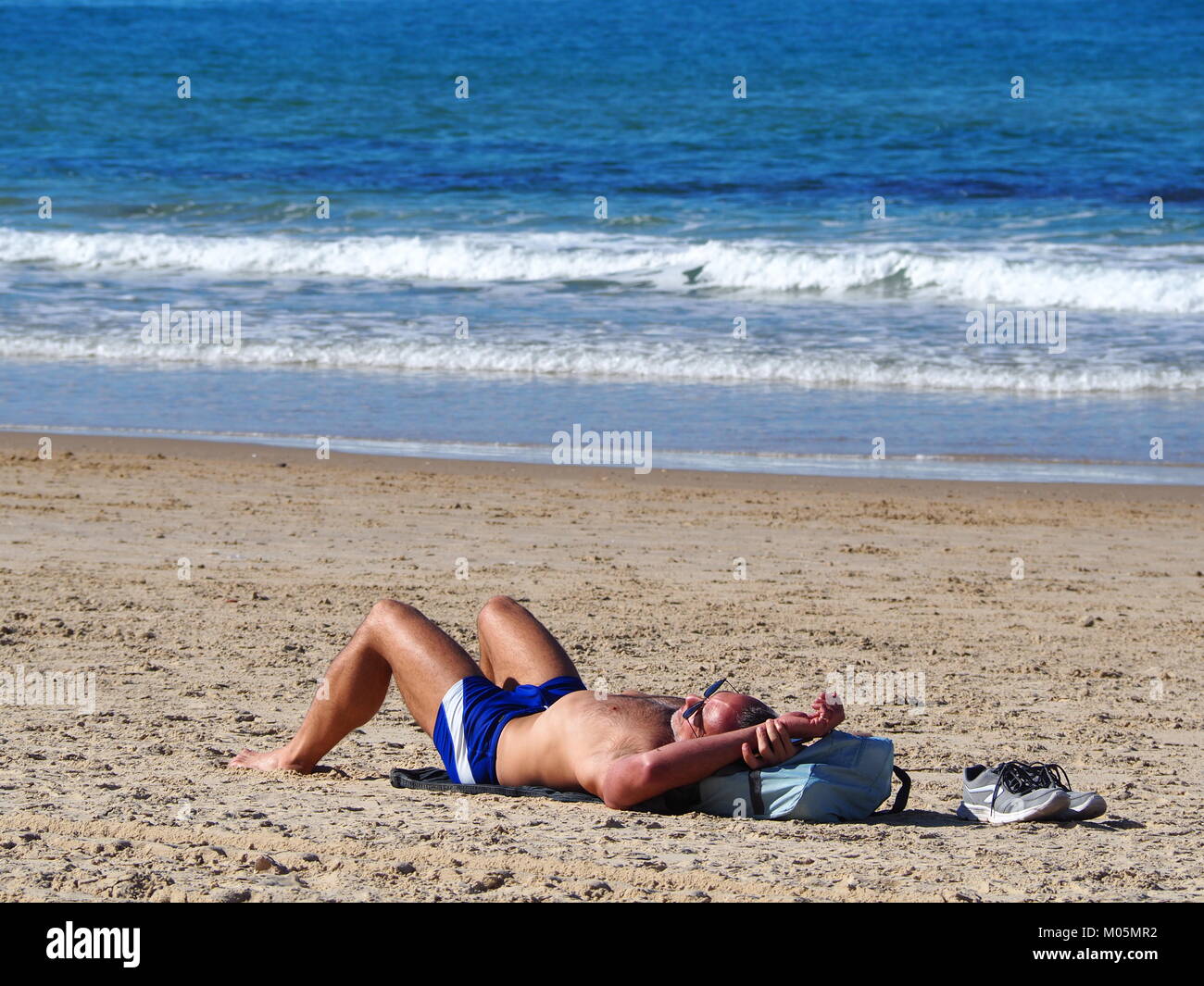 Ricreazione in vacanza - un uomo sta diventando tan sul sdraiati al sole in spiaggia Foto Stock