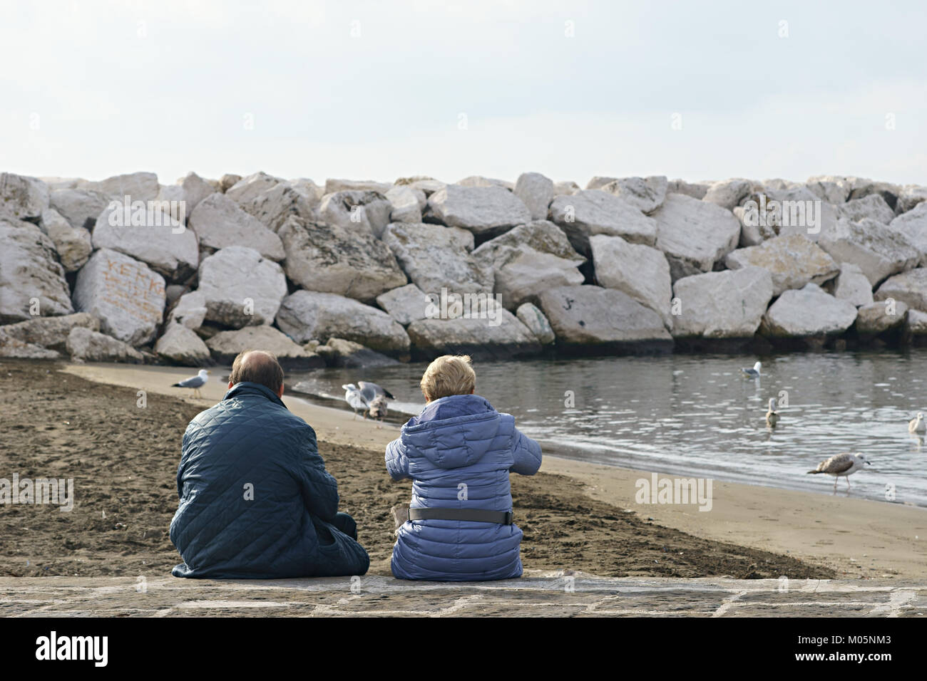 Giovane seduto sulla spiaggia Foto Stock
