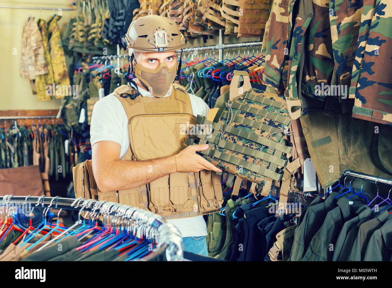 Giovani Svizzeri positivo guy scegliendo flak jacket in negozio militare  Foto stock - Alamy