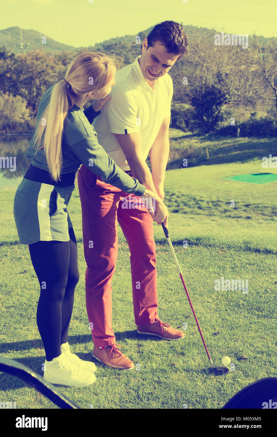 Piuttosto giovane donna golfista uomo di formazione per giocare a golf e colpire la sfera correttamente Foto Stock
