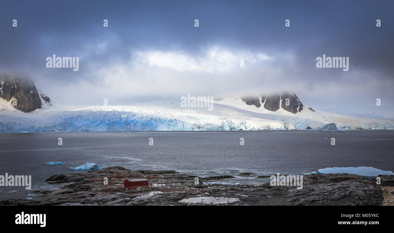 Costa rocciosa panorama di montagne e ghiacciai nascosti nelle nuvole, Peterman island, penisola Antartica Foto Stock
