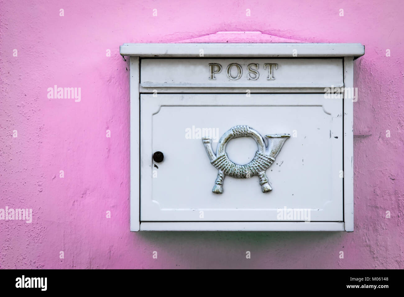 Un bianco di bloccaggio cassetta postale si siede su una parete rosa in Germania. Foto Stock