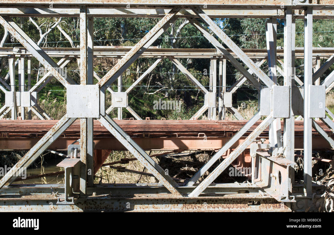 Vista astratta di un vecchio e in disuso parzialmente smantellata ponte costruito con metallo per impieghi pesanti telaio che è ora la formazione di ruggine. Foto Stock