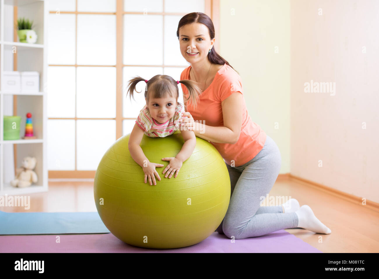Trainer instructor con kid fitness facendo sulla sfera Foto Stock