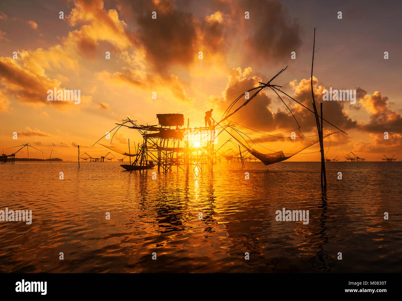 I pescatori intingere la sua rete di sollevamento in acqua per la cattura di gamberetti all'alba ,Phatthalung Thailandia Foto Stock