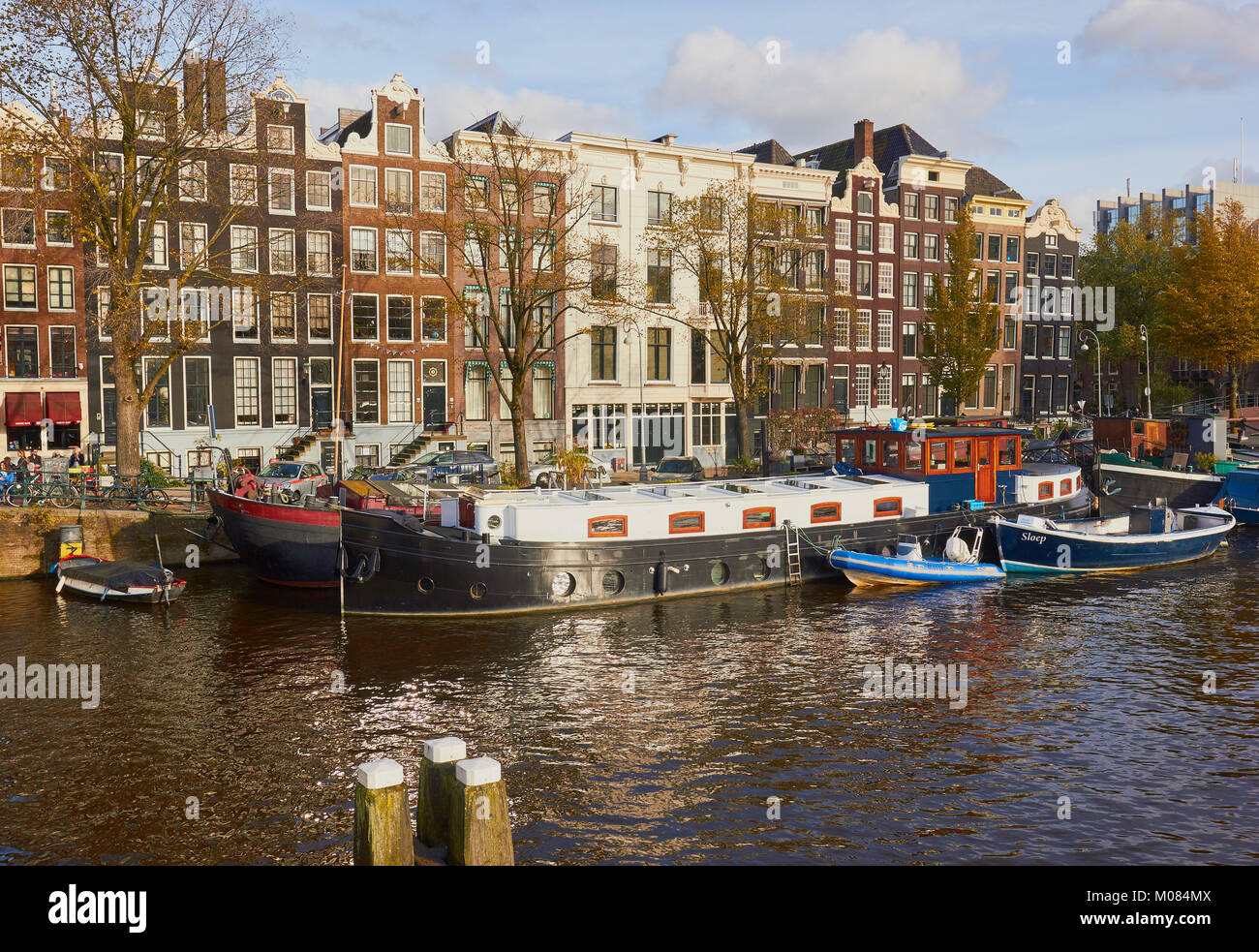 Tipiche case tradizionali, chiatte e battelli fodera sul fiume Amstel di Amsterdam, Paesi Bassi Foto Stock