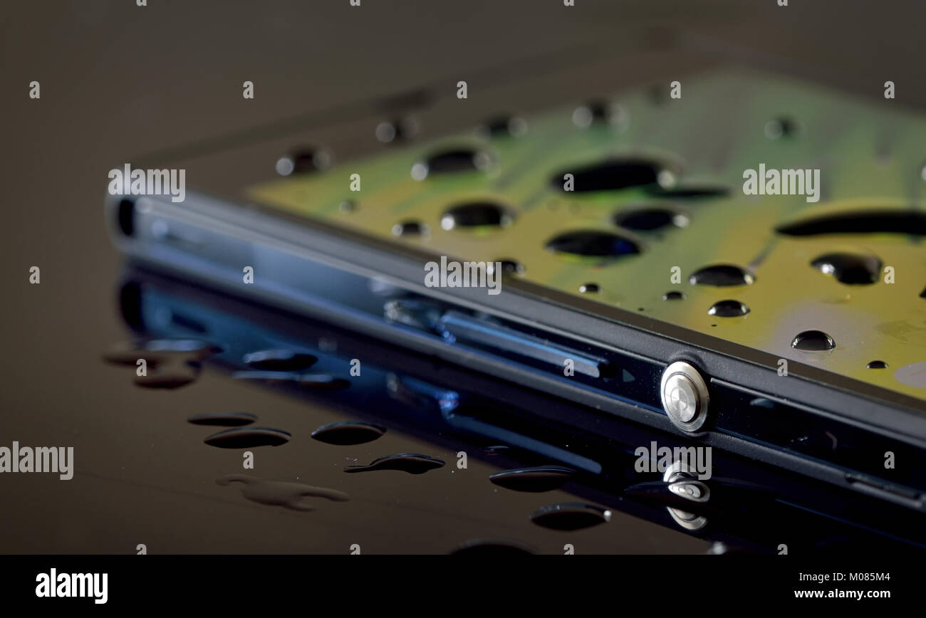 Smartphone impermeabile e rugiada sulla tavola nera Foto Stock