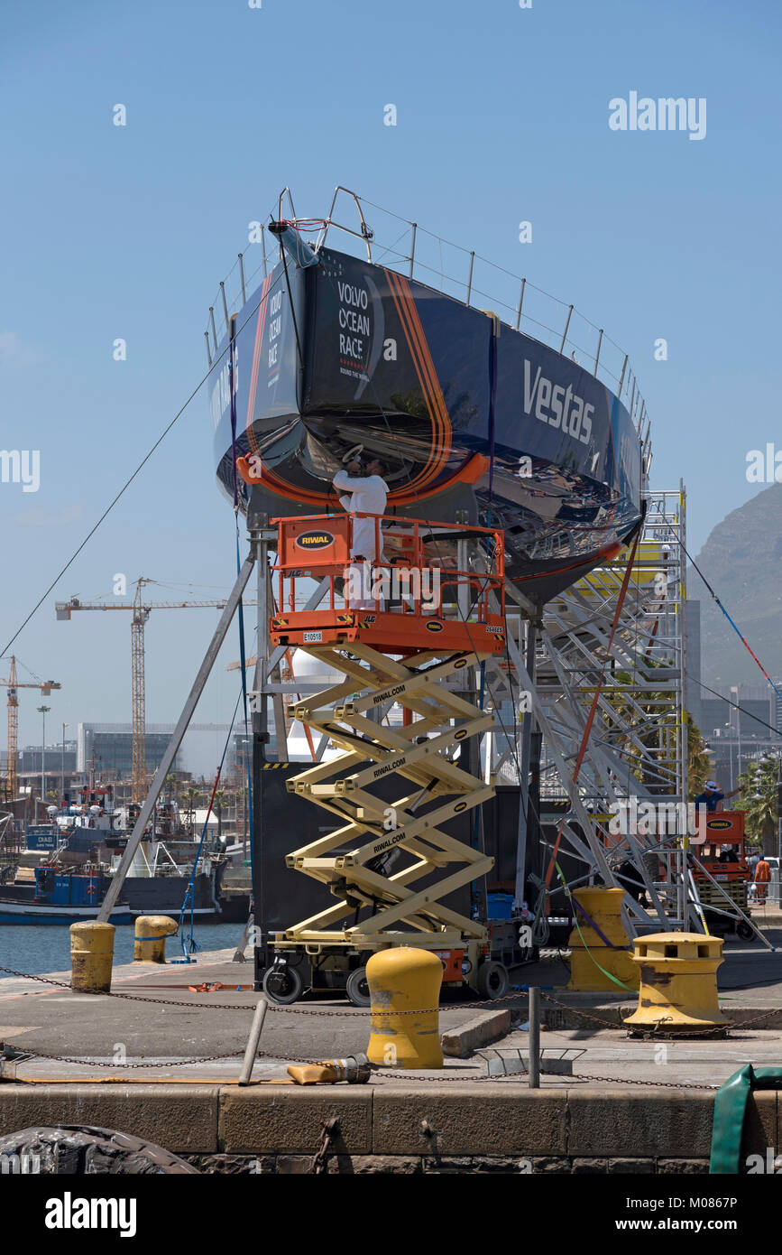 Cape Town Waterfront Sud Africa. Dicembre 2017. Volvo Ocean Race. Racing yacht Vestas. La lucidatura dello scafo da operaio su un elevatore a pantografo pre gara. Foto Stock