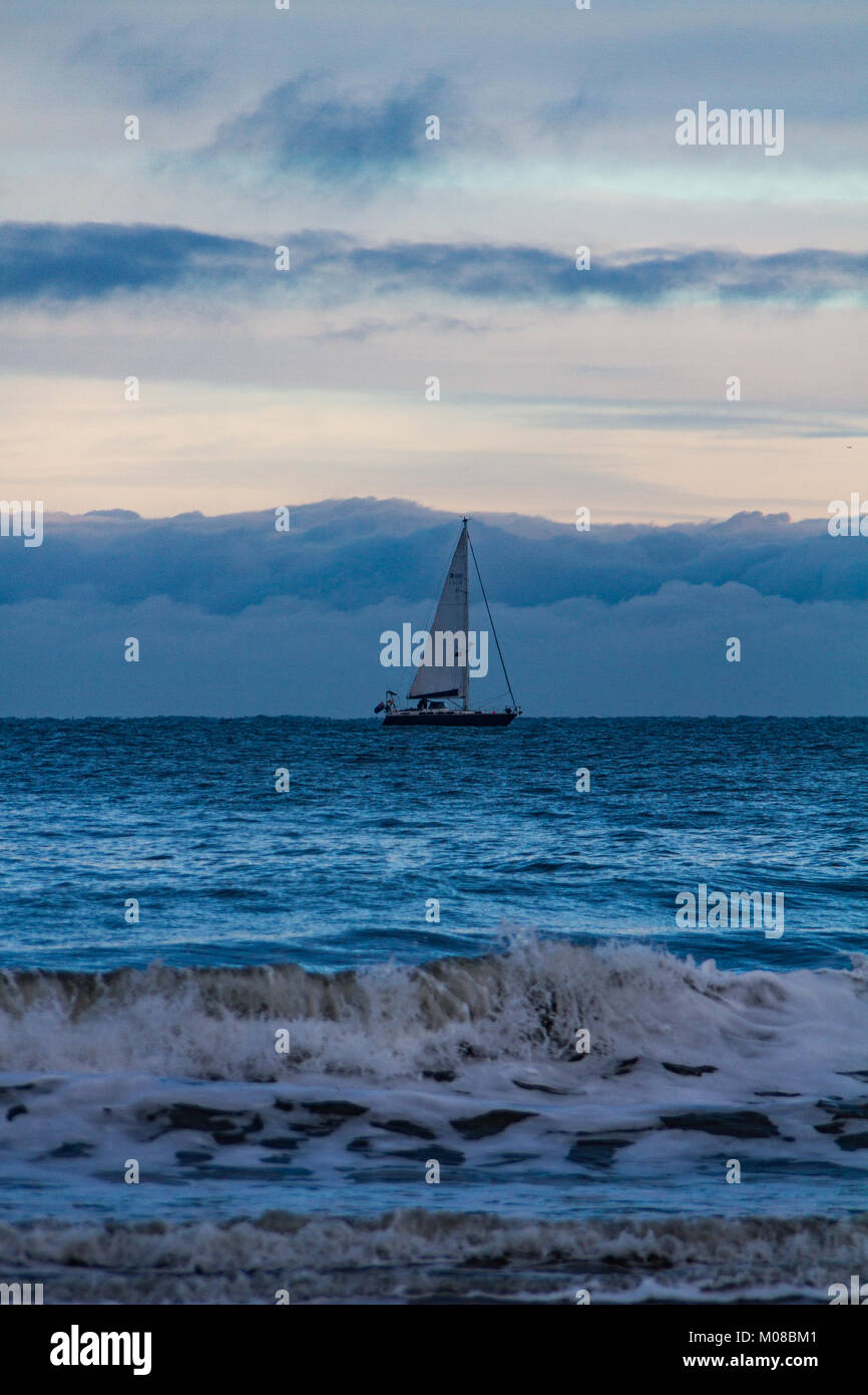 Barca a vela vela in mare mosso off, Tynemouth Regno Unito in una fredda mattina di inverno Foto Stock