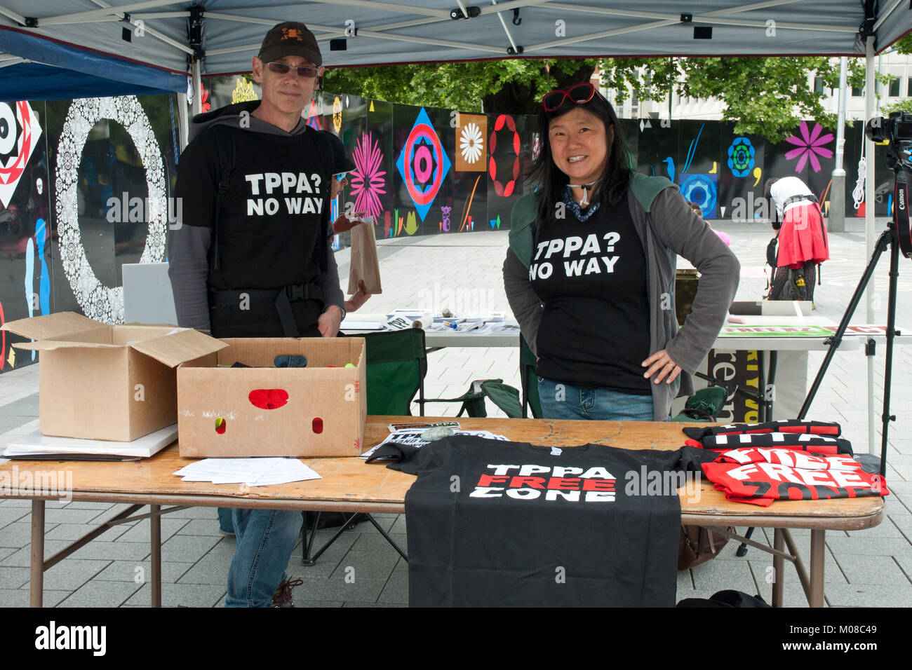 Rally contro TPP/ trans pacific partnership in Christchurch, Nuova Zelanda, con due giovani attivisti di indossare magliette 'TPPA NESSUN MODO' dietro di stallo. Foto Stock