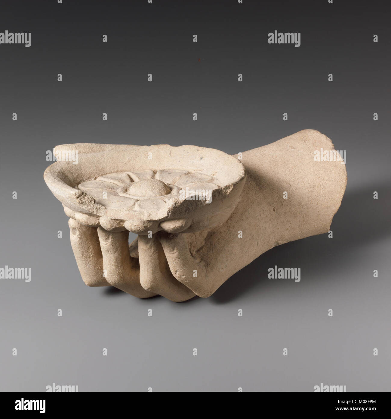 Questa scultura calcarea raffigura una mano che tiene in mano una fiale (ciotola di libagione), che rappresenta le pratiche rituali nell'antico Egitto. Foto Stock