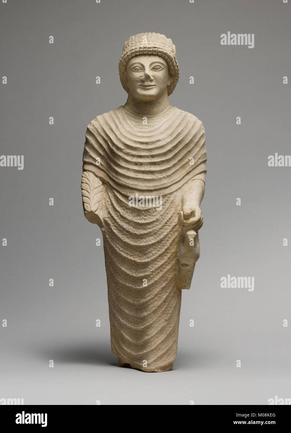 Una statua calcarea di un elettore maschio che tiene un uccello nella mano sinistra, che illustra antiche offerte religiose e pratiche votive. Foto Stock