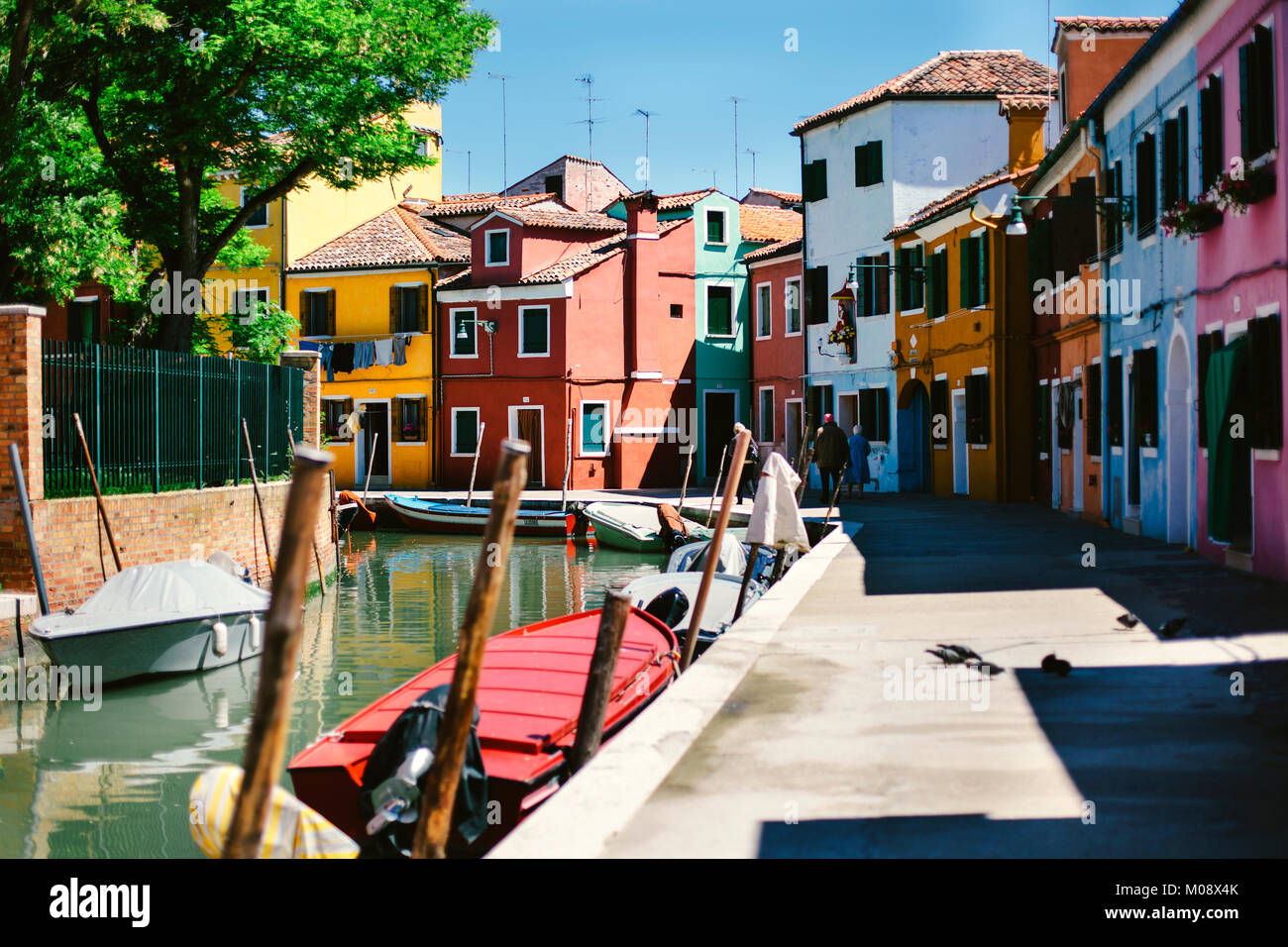 Svuotare canal street con barche parcheggiata e case colorate in mattina durante la bassa stagione in isola di Burano, Venezia, Italia. Foto Stock