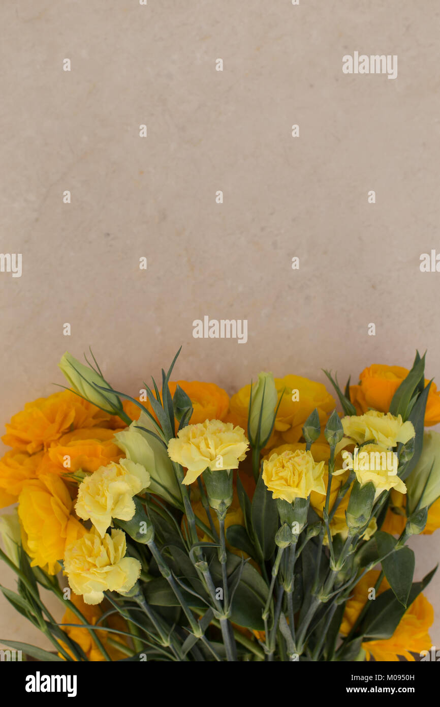 Giallo garofani e ranunculus sul tavolo di marmo. Composizione verticale. Copia dello spazio. Foto Stock