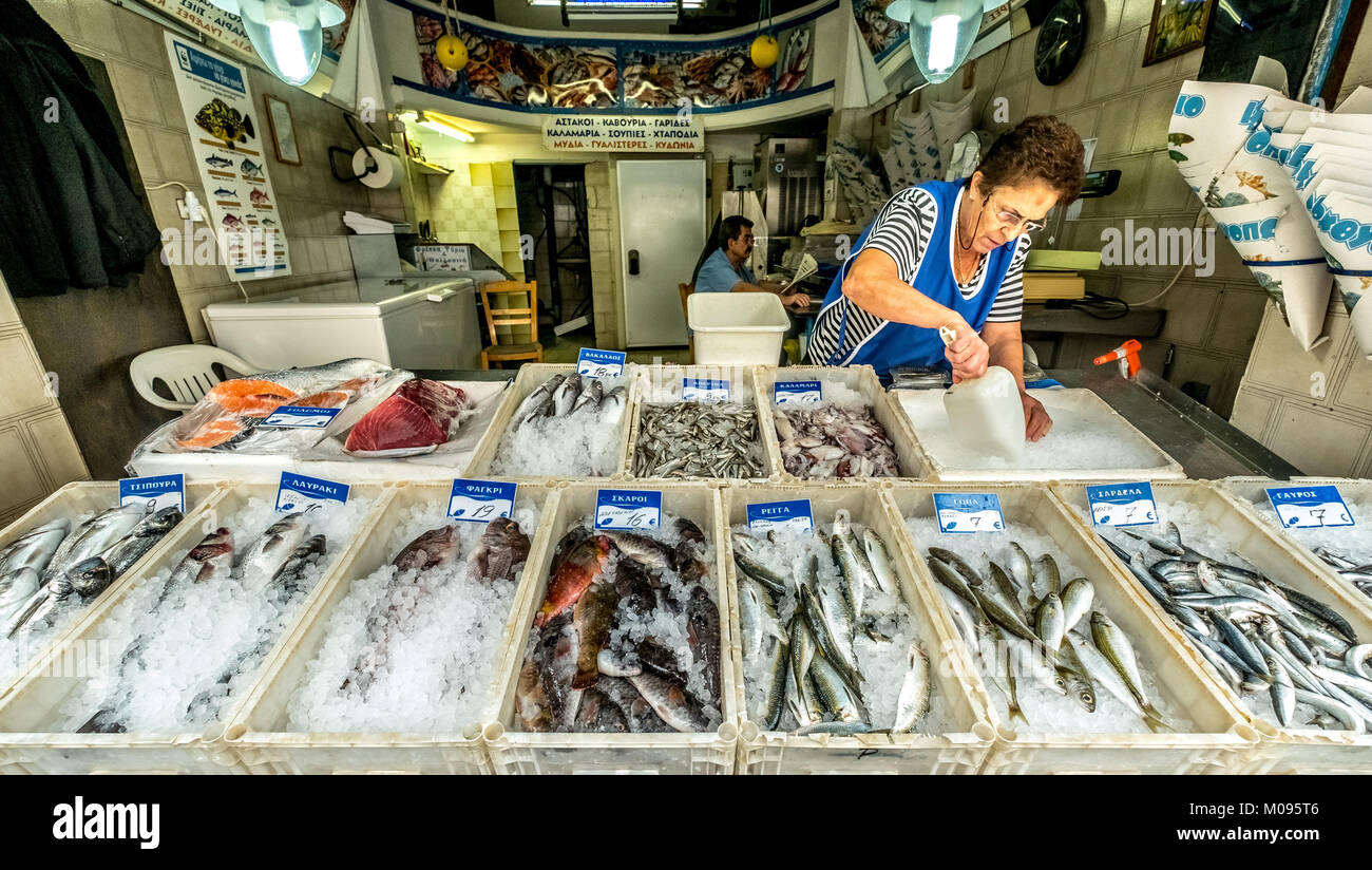 Pescivendolo nel pescivendolo shop nelle strade di Rethimno, orate, orecchio pesce, sardine, acciughe, orate, spigole, aringa, pesce su ghiaccio, Foto Stock