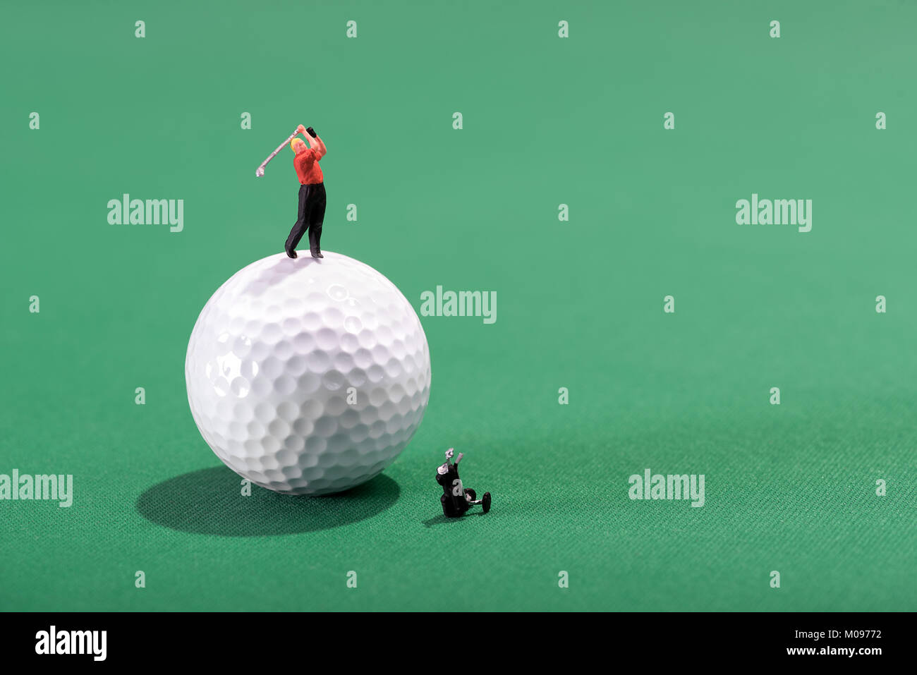 Giocatore di golf in miniatura di rinvio-off da sulla parte superiore di una sfera su un verde baize sfondo con spazio di copia Foto Stock