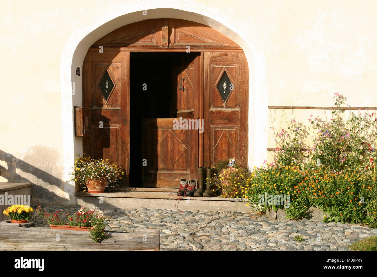 Grandi in legno porta ad arco in corrispondenza di case a Guarda, Svizzera Foto Stock