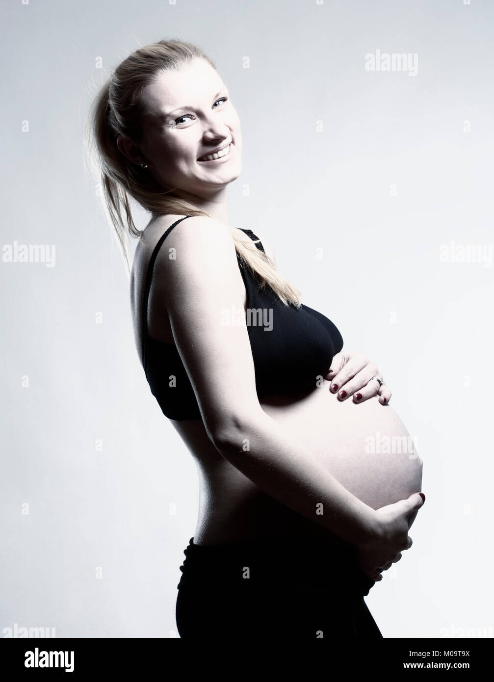 Ritratto di una gravidanza donna bionda nel reggiseno nero. Foto Stock