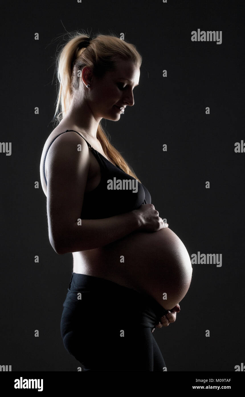 Ritratto di una gravidanza donna bionda nel reggiseno nero. Foto Stock