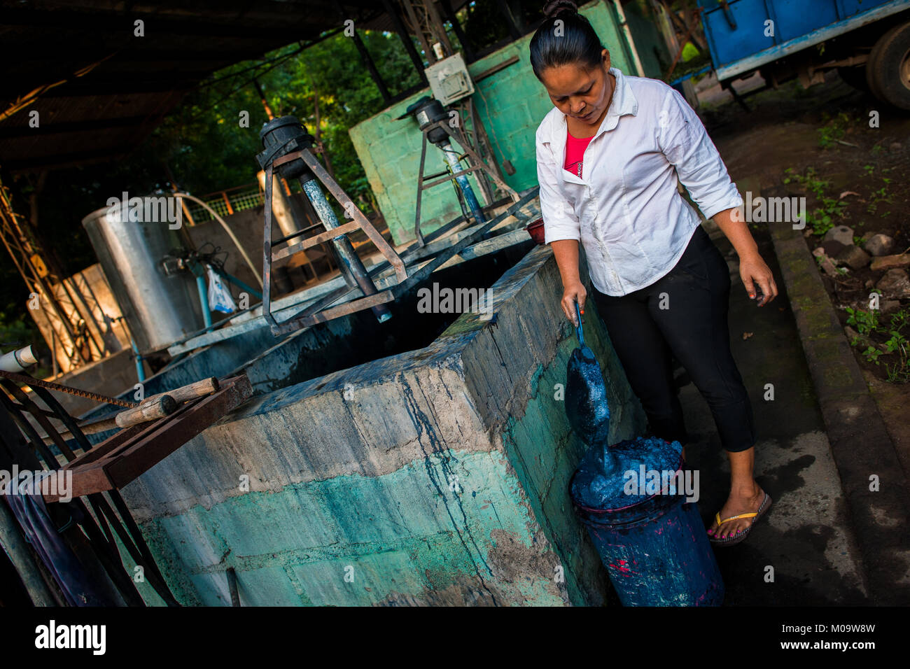 Una fattoria di Salvadoran lavoratore raccoglie schiuma blu dalla parte superiore della soluzione di acqua in un serbatoio a fabbricazione vicino a San Miguel, El Salvador. Foto Stock