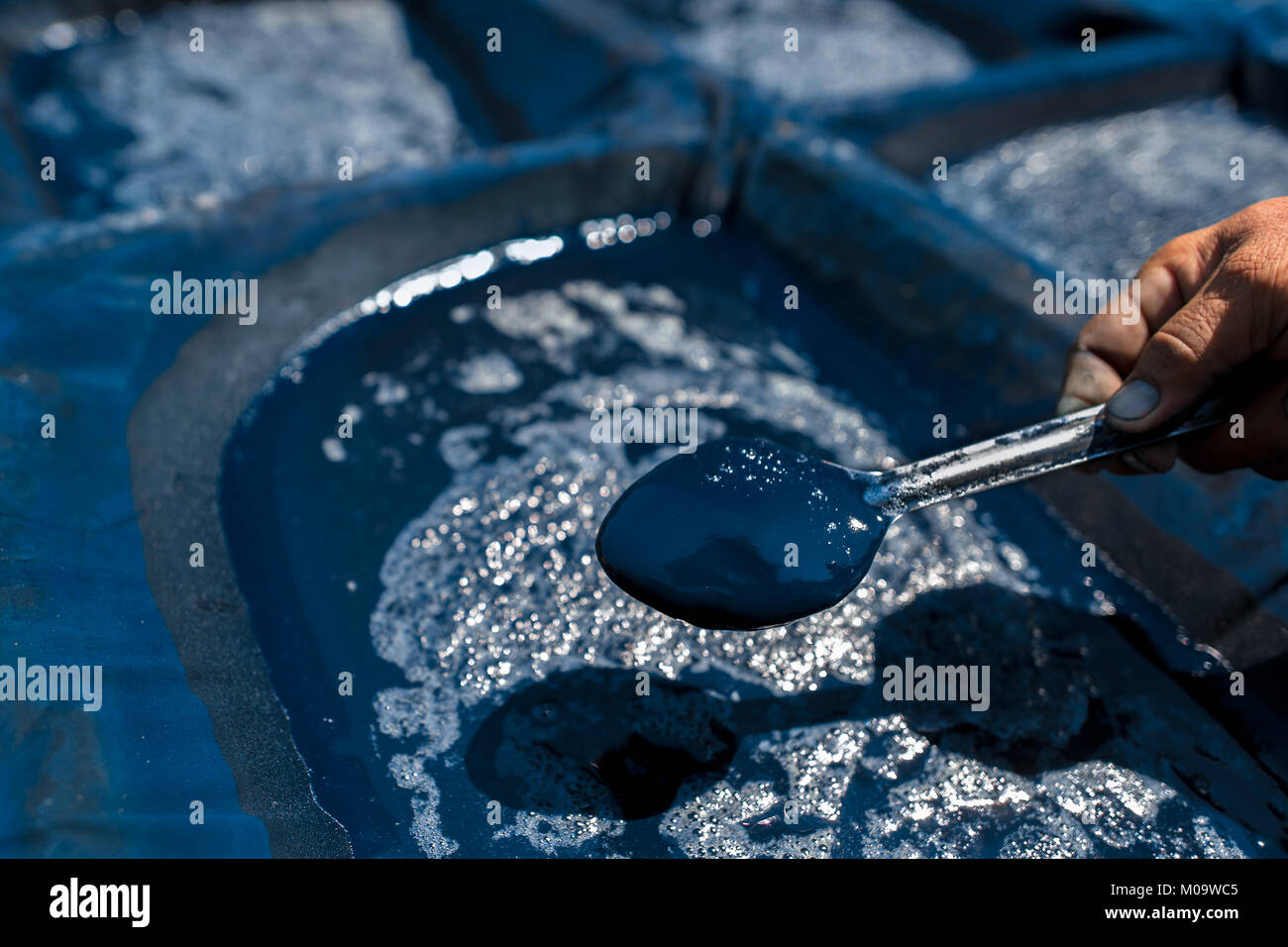 Lavoratore agricolo controlla il pigmento indaco pur essendo filtrata al sole nel semi-fabbricazione industriale vicino a San Miguel, El Salvador. Foto Stock