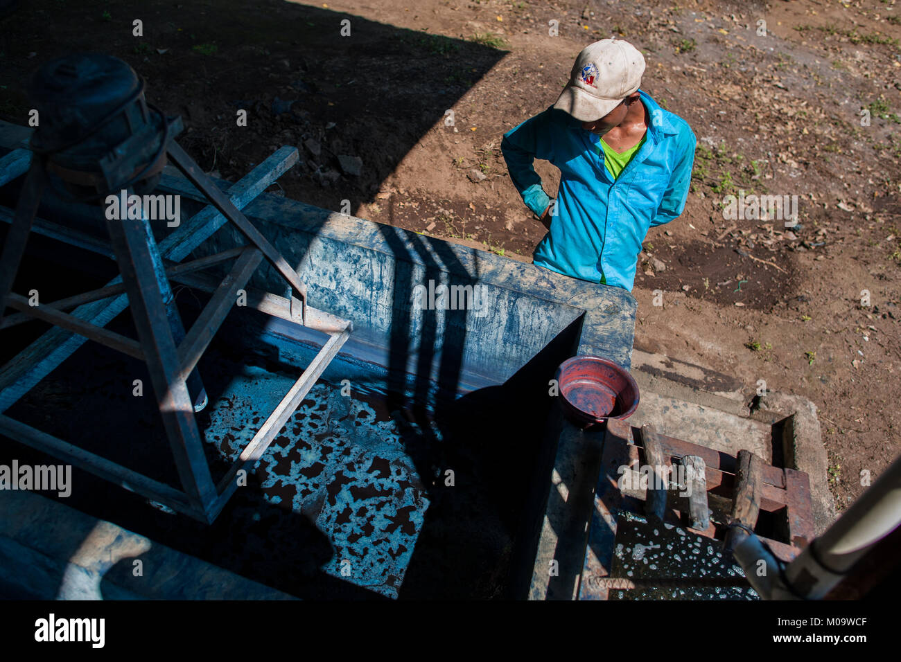 Una fattoria di Salvadoran lavoratore controlla la indigo elaborazione al semi-fabbricazione industriale vicino a San Miguel, El Salvador. Foto Stock