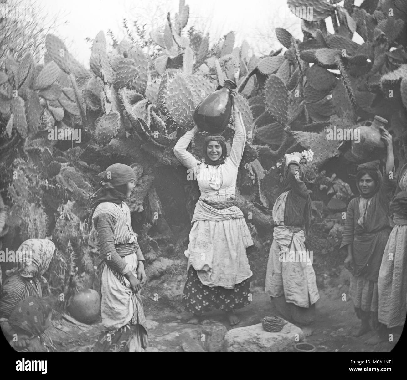 Fine del XIX secolo o agli inizi del XX secolo fotografia in bianco e nero che mostra un gruppo di donne al pozzo di Cana in Israele. Le donne sono la raccolta di acqua in grandi brocche d'acqua e li porta indietro sulle loro teste. Foto Stock