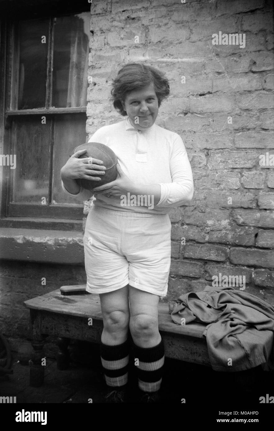 Foto in bianco e nero degli inizi del XX secolo che mostra una donna vestita di un gioco del calcio (calcio) kit e holding e vecchio stile di calcio in pelle. Foto Stock