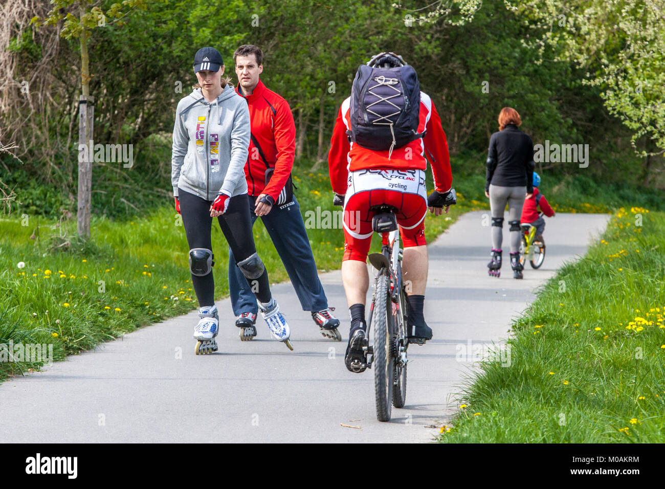 Persone attive pattinaggio in linea sulla pista ciclabile persone sulla pista ciclabile persone sulla pista ciclabile persone sui pattini in linea passano un ciclista sulla pista ciclabile pattinatori in linea Man Foto Stock