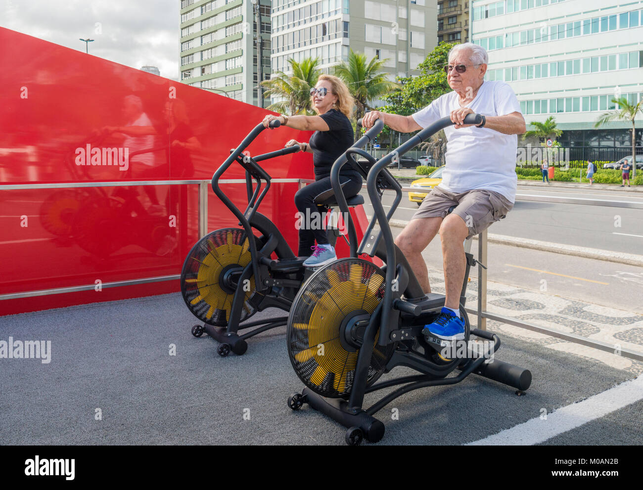 Modello rilasciato: uomo vecchio (80-89) e la donna più anziana (70-79) che esercitano sui percorsi in bicicletta la macchina a palestra a cielo aperto in Rio de Janeiro, Brasile Foto Stock