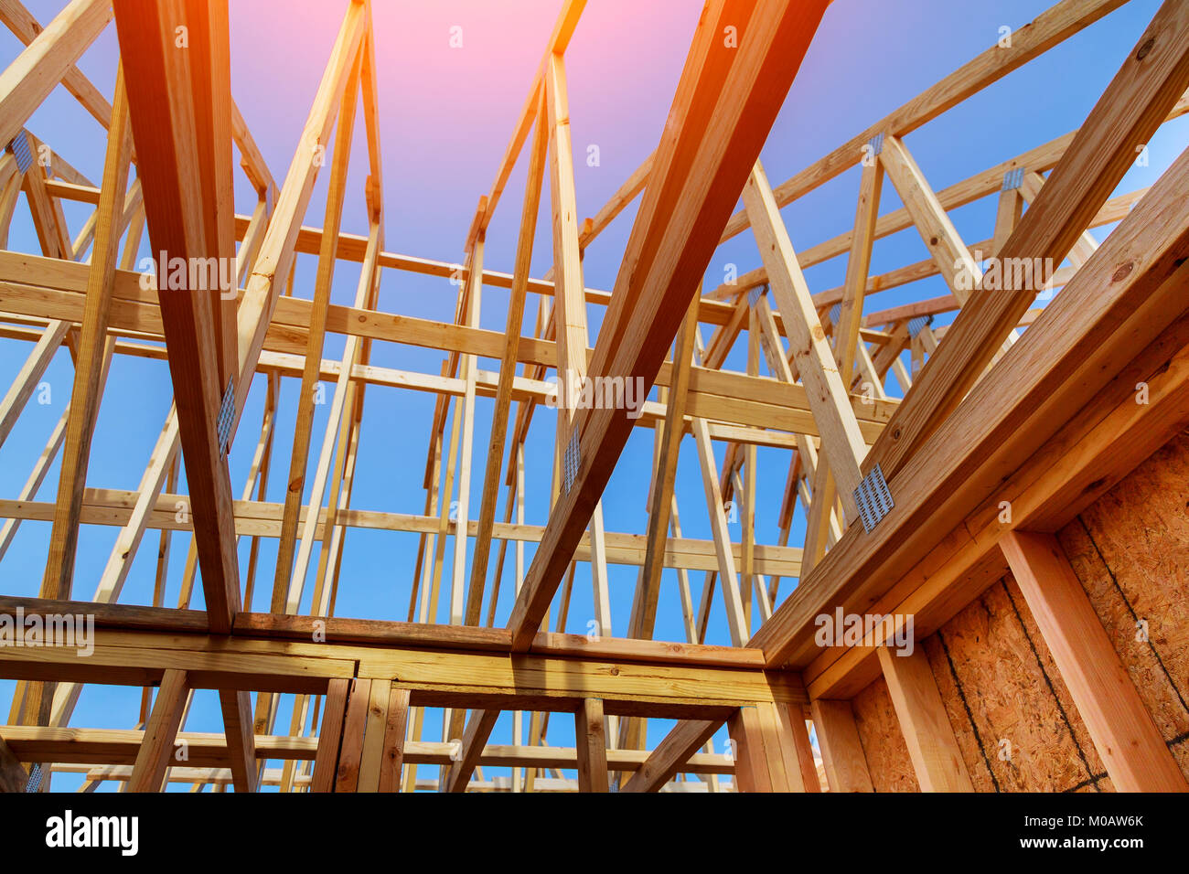 Close-up di gables tetto su stick costruita casa in costruzione e cielo blu di nuova costruzione con tetto di travatura reticolare di legno, travi e i framework. Telaio in legno ho Foto Stock