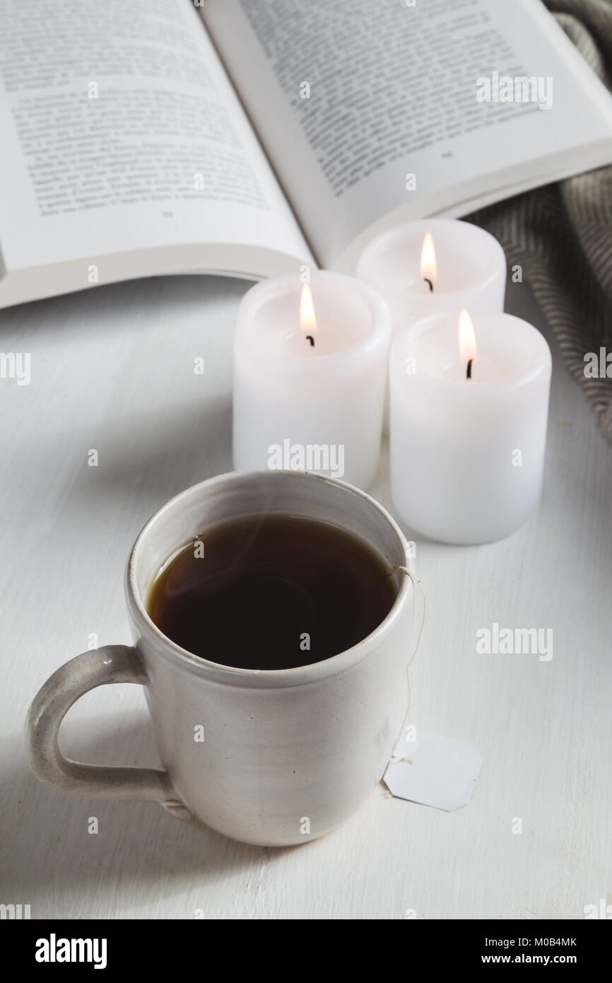 La tazza di tè con candele prenota e intima coperta Foto Stock