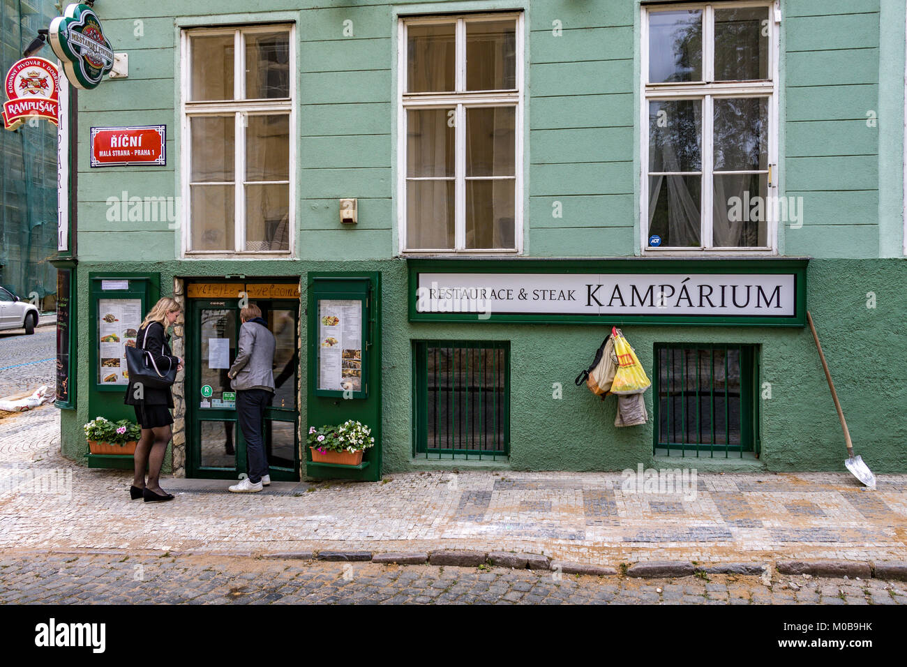 Una coppia entra Kamparium, un ristorante di bistecca a Praga, situato lungo una strada acciottolata in Malá Strana, Praga, Repubblica Ceca Foto Stock