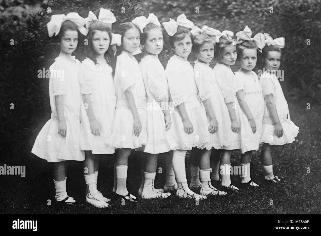 Line up della bella Kindergartners in una fila di indossare abiti di colore bianco Foto Stock