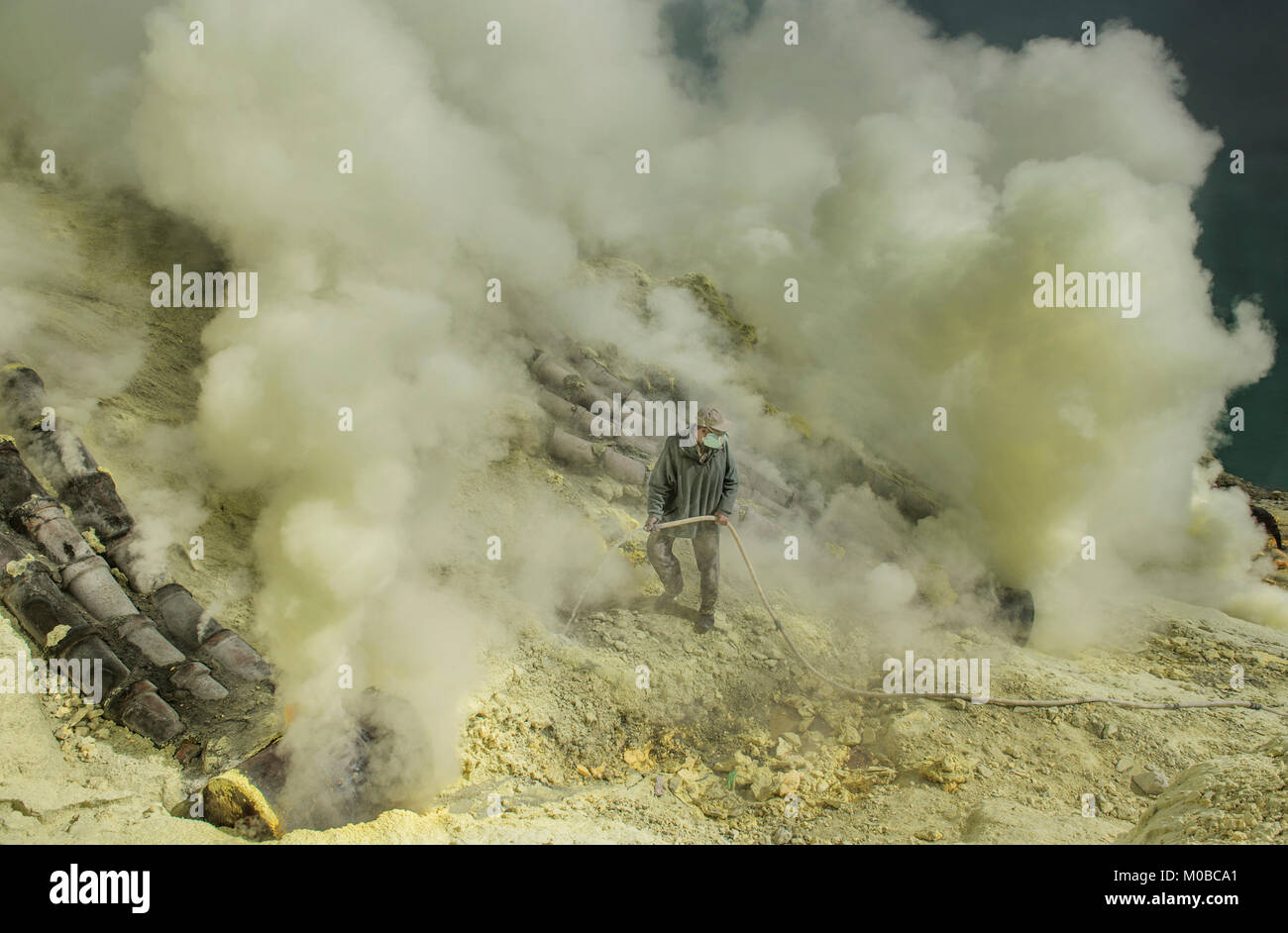 Ranger è circondato da gas tossici cercando di mettere dell'eccesso di fumo dal tubo di scarico aumenta la produzione di zolfo in Kawah Ijen mountain, Indonesia Foto Stock