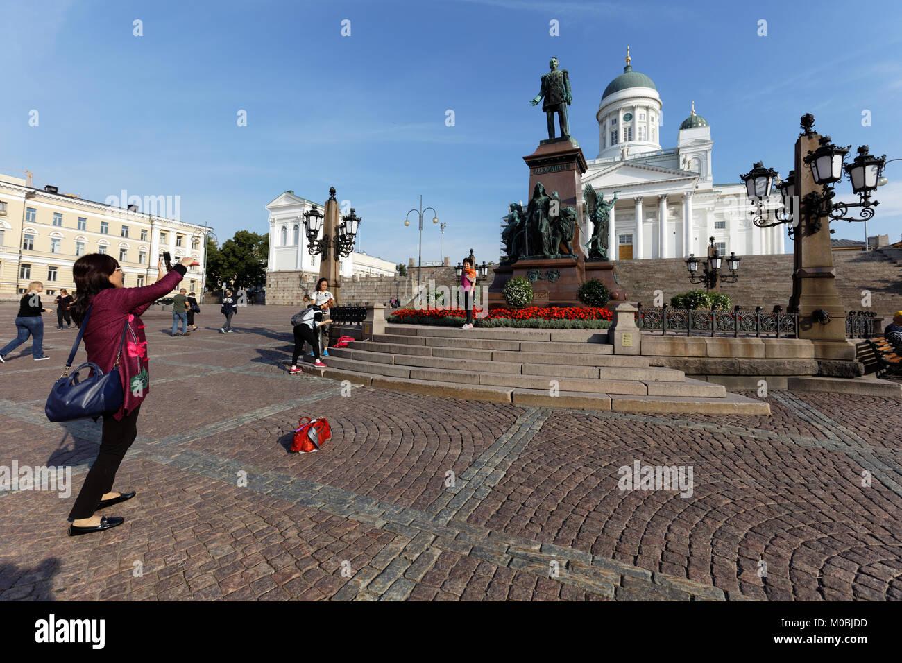 Helsinki, Finlandia - 21 agosto 2016: turisti cinesi fare foto contro la statua dell'imperatore russo Alessandro II sulla Piazza del Senato. La statua, ere Foto Stock