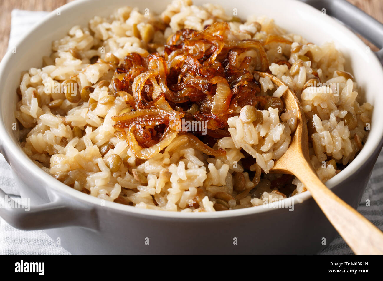 Cibo vegetariano: riso con le lenticchie e cipolle caramellate macro in un recipiente orizzontale. Foto Stock