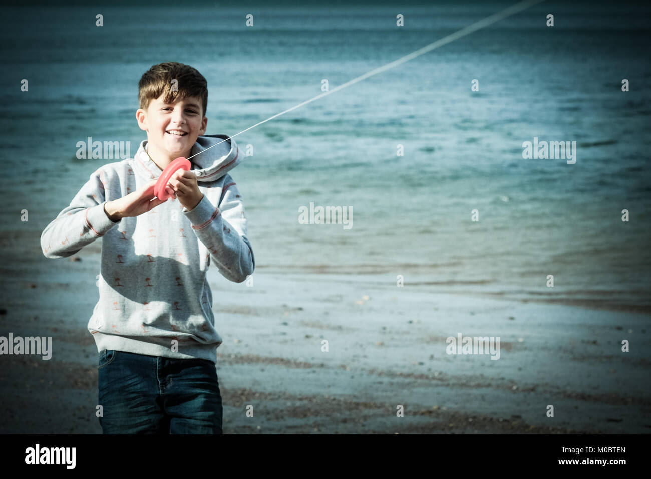 10 anno vecchio ragazzo volare un aquilone di mare a Runswick Bay, Yorkshire, Regno Unito Foto Stock