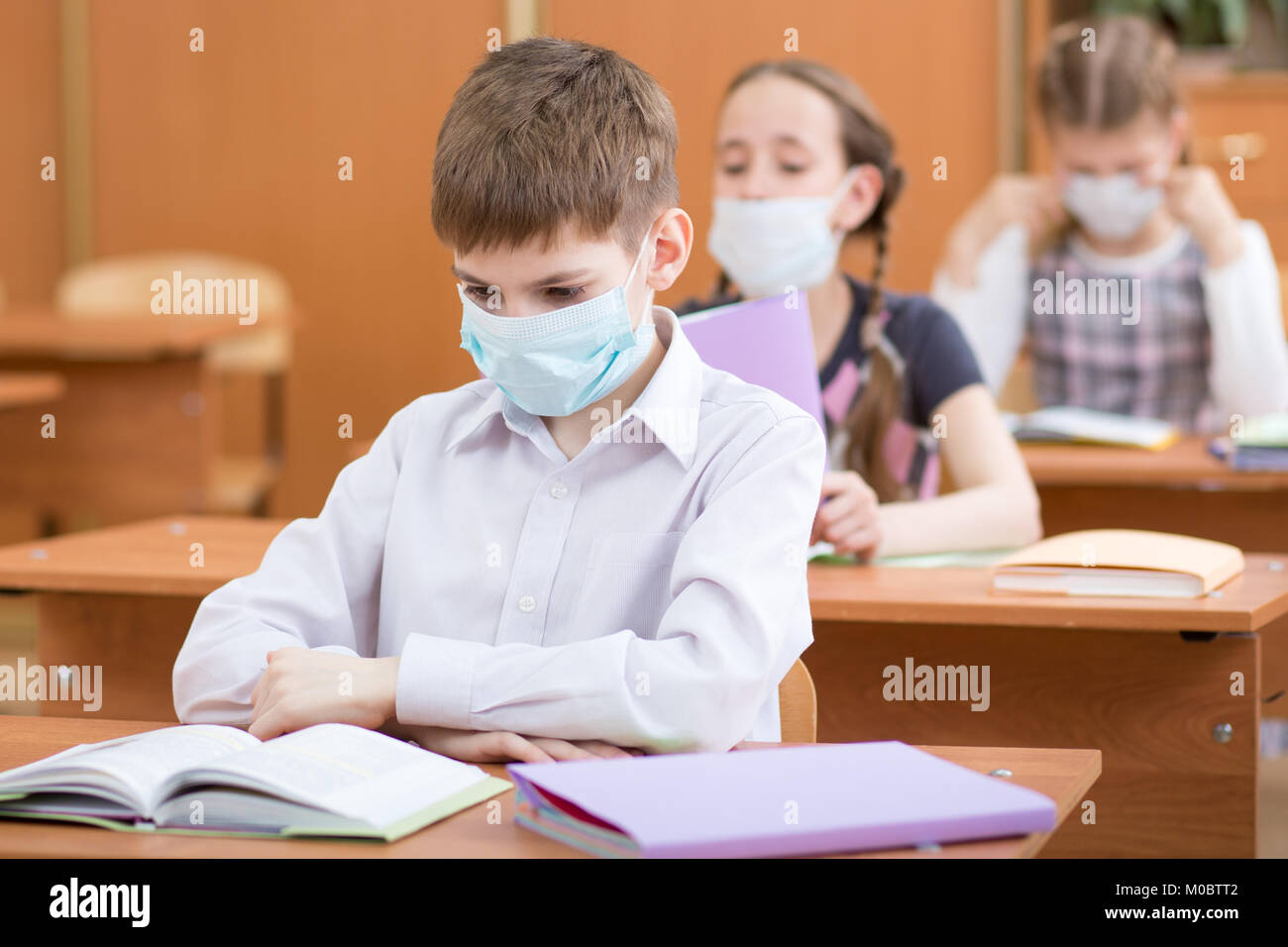 La scuola dei bambini con maschere di protezione contro virus influenzale a lezione in aula Foto Stock