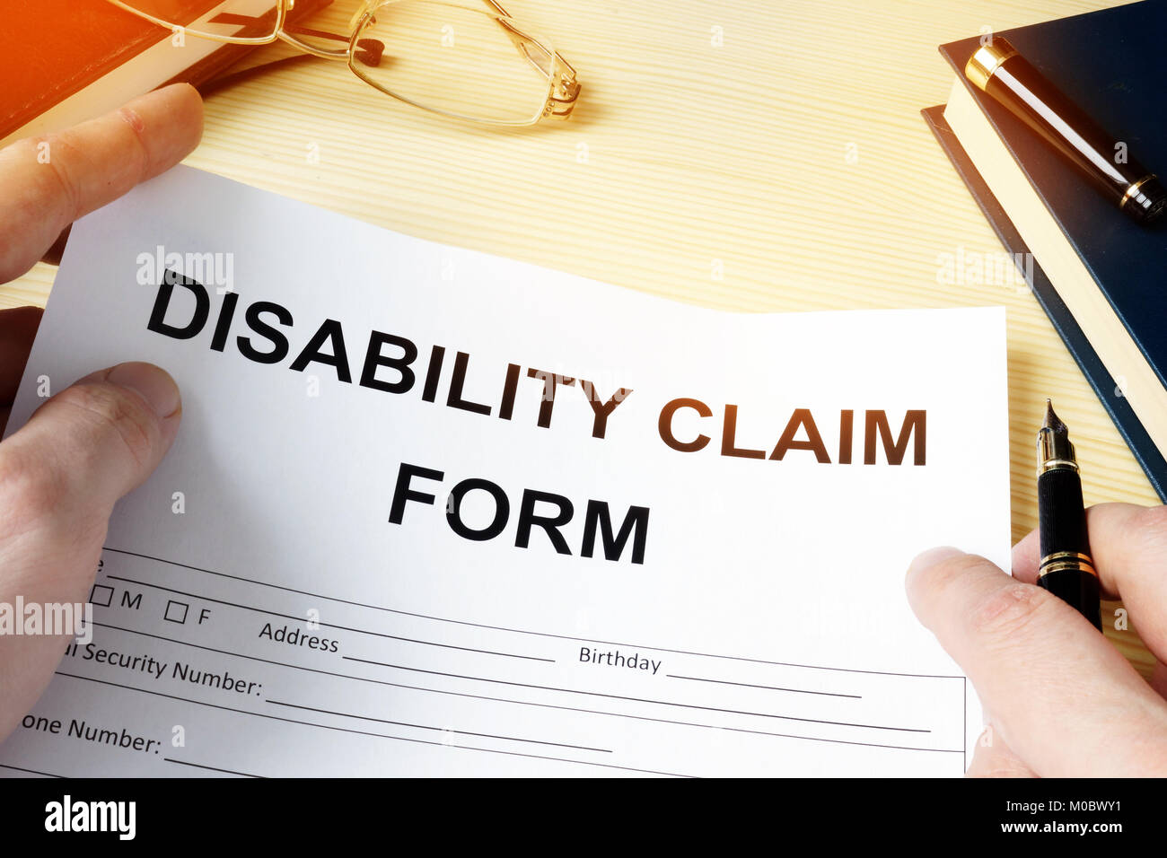 Uomo con disabilità sul modulo di richiesta di rimborso per la copertura assicurativa. Foto Stock