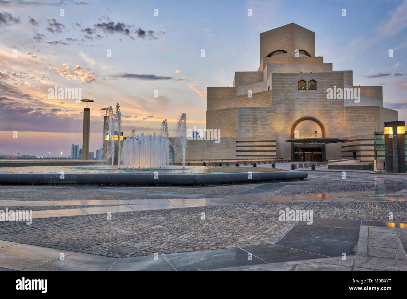 Il Museo di Arte islamica ,,di Doha in Qatar nella luce diurna e vista esterna con fontana in primo piano e le nuvole nel cielo in background Foto Stock