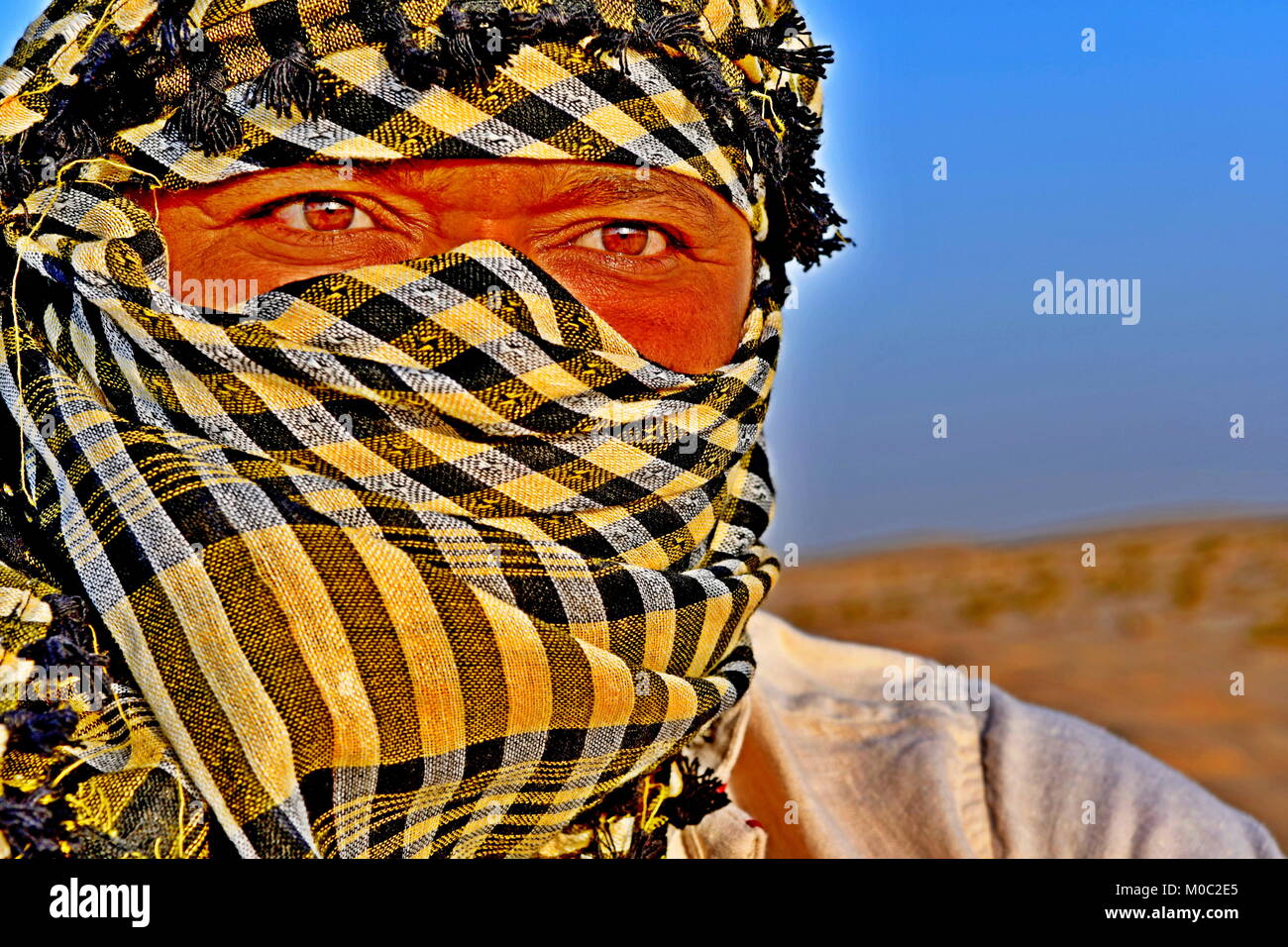 Close up ritratti di uomo Arabo nel deserto indossando una sciarpa di testa come una tradizione di cultura Foto Stock