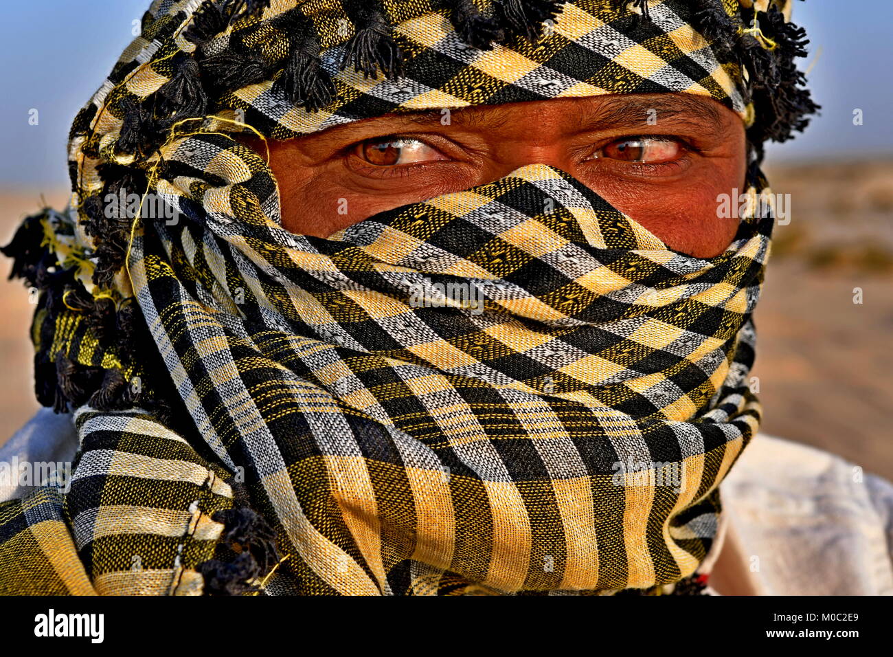 Close up ritratti di uomo Arabo nel deserto indossando una sciarpa di testa come una tradizione di cultura Foto Stock