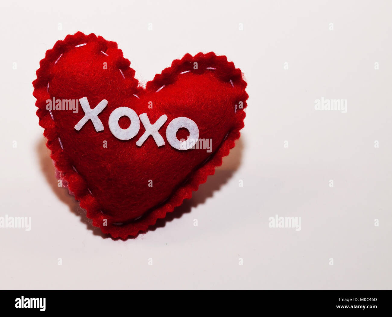 Un rosso panno fatti a mano nel cuore con 'XOXO' scritta attraverso la parte anteriore di essa. Vi è spazio per il testo aggiunto in shot Foto Stock