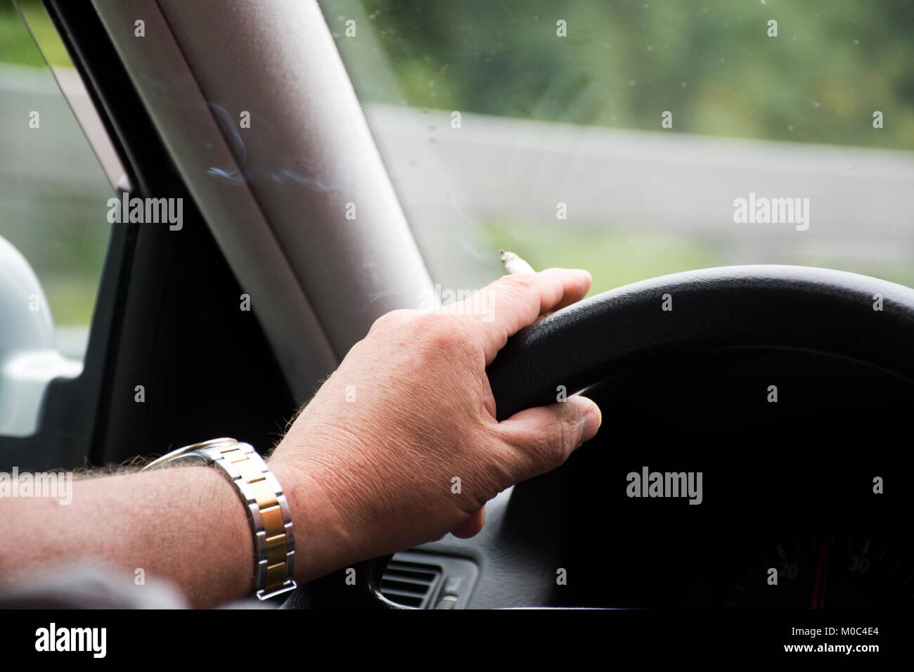 Il tedesco vecchio uomo alla guida di auto molto veloce e di fumare sigaretta sulla autostrada di Stoccarda andare in Austria e in Italia il 1 settembre 2017 a Stoccarda, Germania Foto Stock