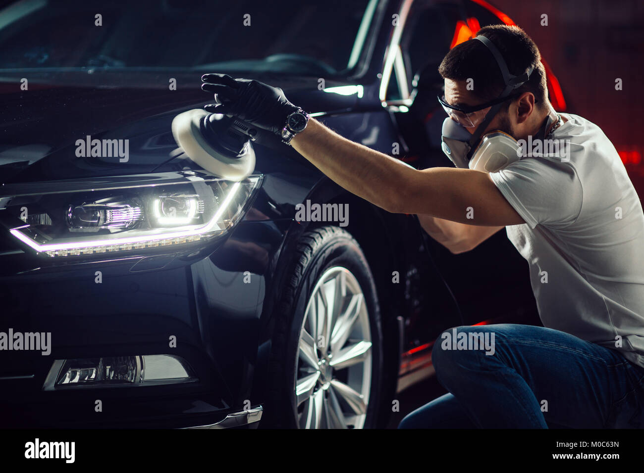 Dettagli auto - uomo con lucidatrice orbitale nel negozio di riparazioni auto. Messa a fuoco selettiva. Foto Stock