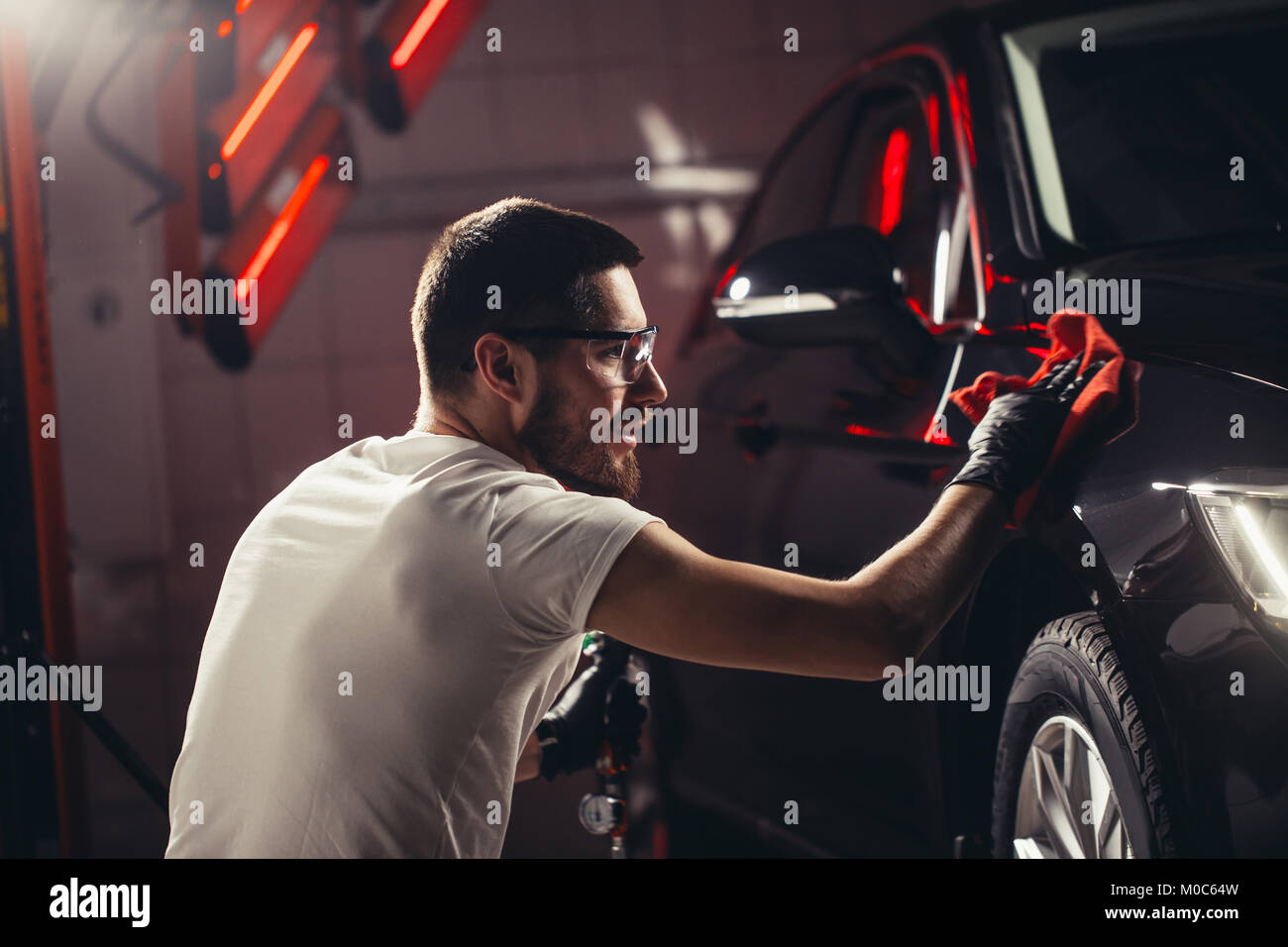 Dettagli auto - l'uomo detiene la microfibra in mano e leviga la vettura Foto Stock